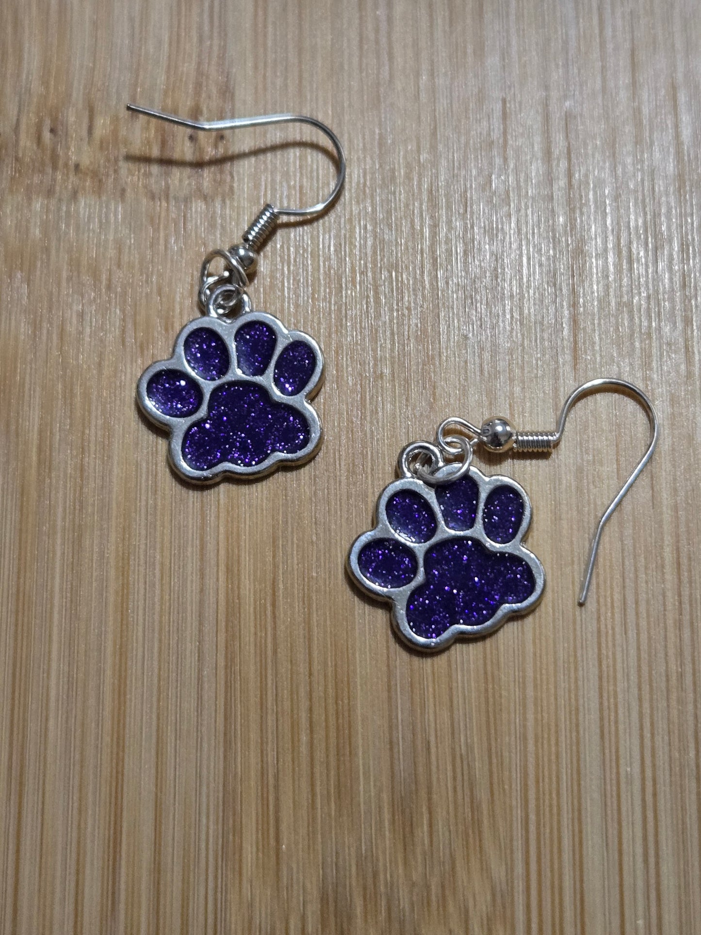 Purple paw print earrings on a wooden surface