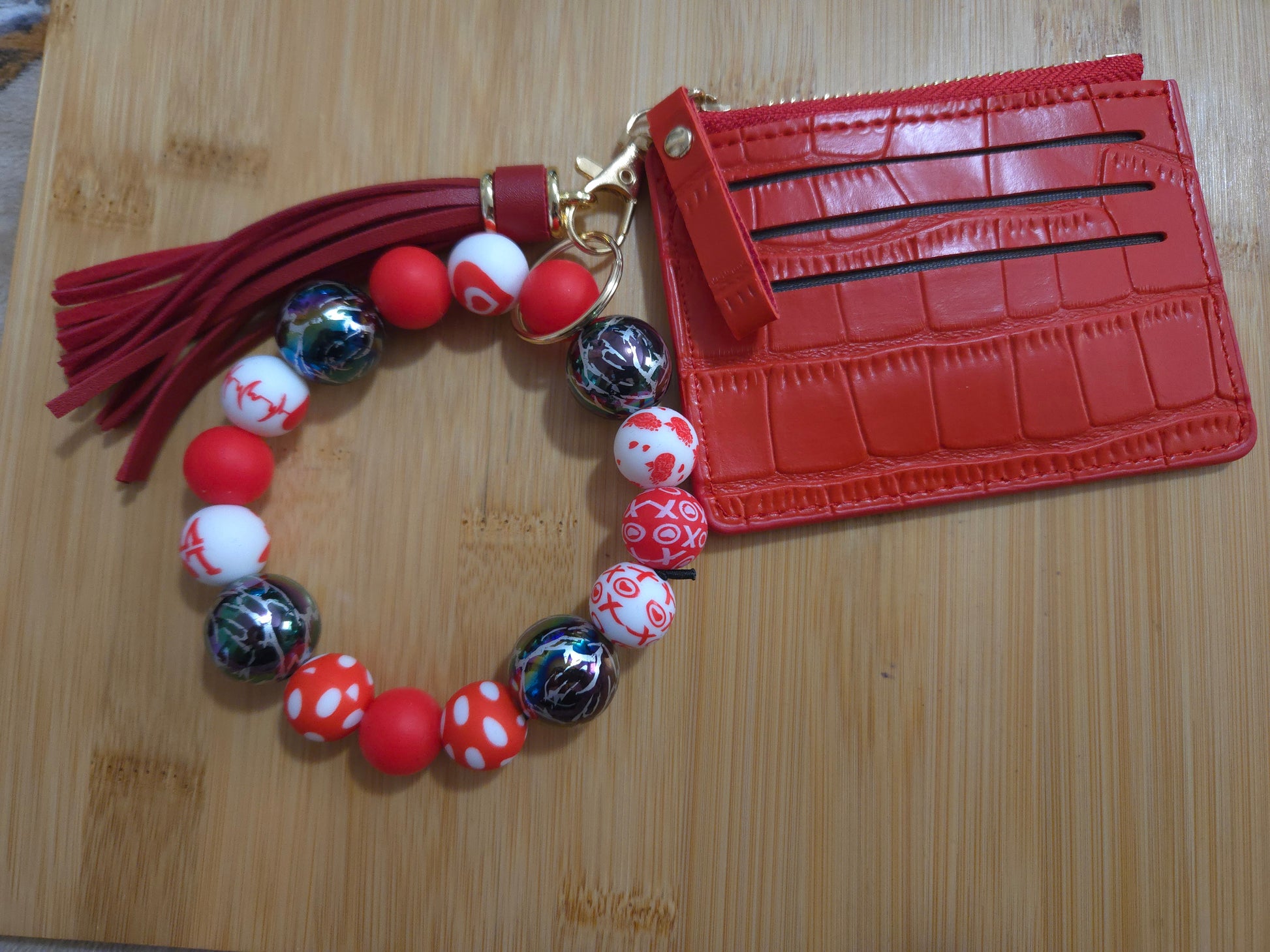 Red beaded bracelet with tassel and red cardholder on a wooden surface