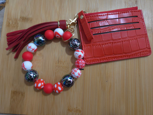 Red beaded bracelet with tassel and red cardholder on a wooden surface