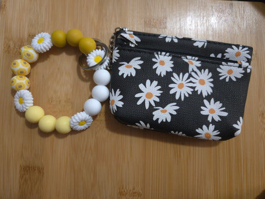 Yellow beaded bracelet with floral design and black pouch with white floral pattern on a wooden surface