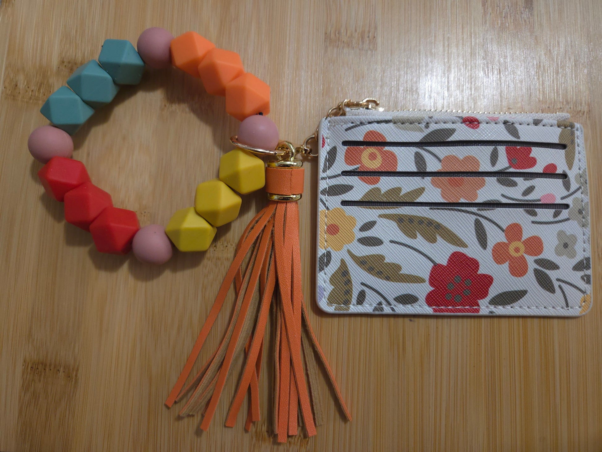 Colorful geometric bracelet with tassels and a floral cardholder on a wooden surface