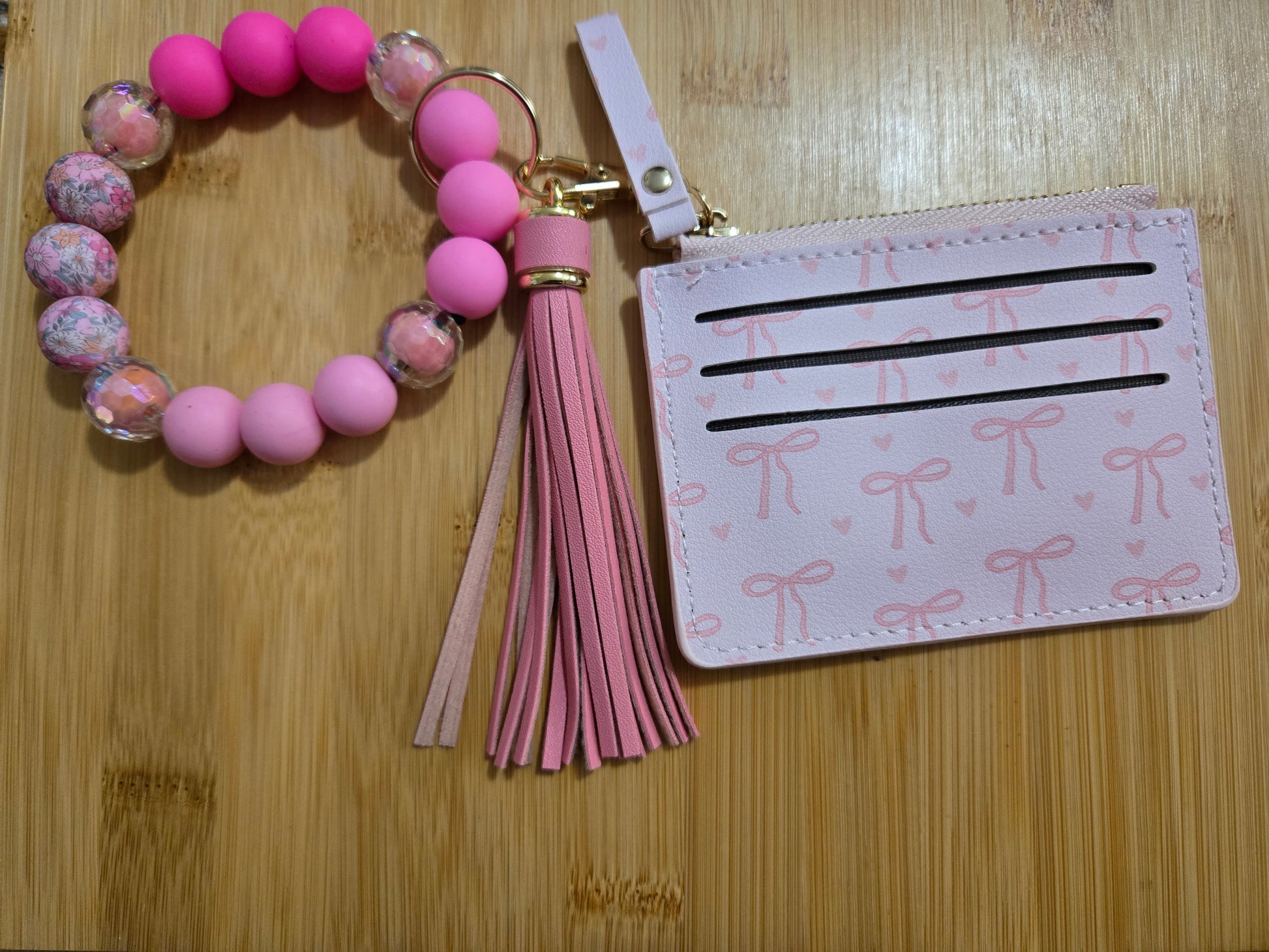 Pink beaded keychain with tassel and matching cardholder on a wooden surface